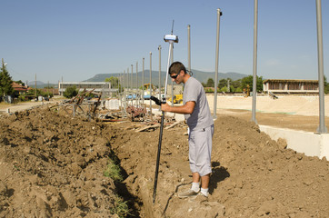 Geodesist measures at a countryside stadium