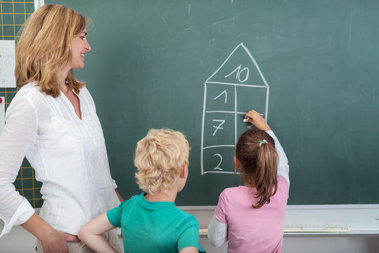 lehrerin unterstützt kinder beim rechnen an der tafel