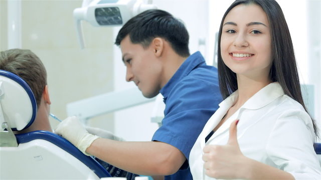 The dentist examines the teeth and smiles at him and the girl
