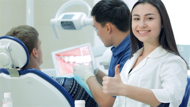 Dentist shows a patient at tablet image of white teeth