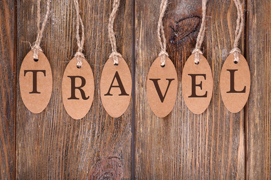 Travel incription on brown tags on wooden background