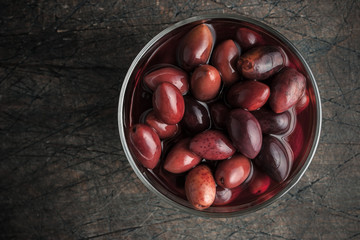Kalamata olives on the glass dish on the old wooden table