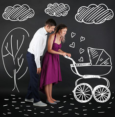 Young couple with baby carriage, on black background