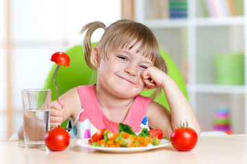 Little girl with expression of disgust against tomato