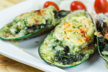 Mussels under cheese on wooden table