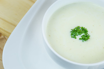 Cream soup in white bowl on wooden table