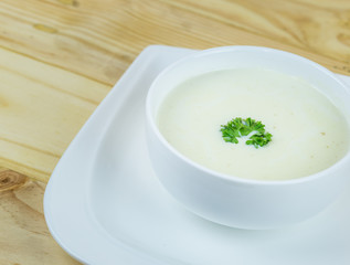 Cream soup in white bowl on wooden table