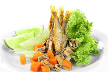 Fried small fish with lettuce and lime on plate close up