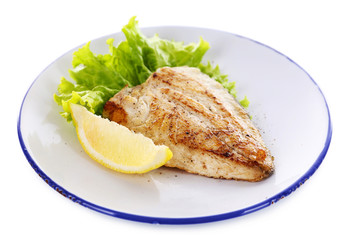 Dish of fish fillet with lettuce and lemon on plate close up