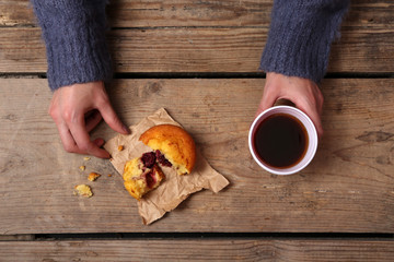 Female hands holding cup of coffee and cookies on wooden table close up