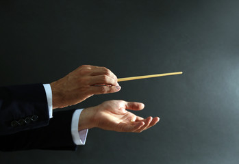 Music conductor hands with baton on black background