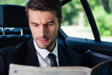 Businessman reading newspaper while riding in car