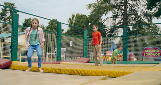 Energetic kids jumping on trampoline in entertainment park 