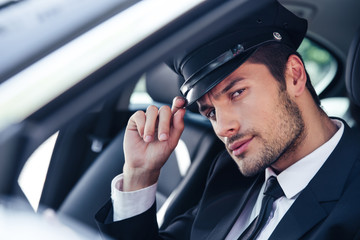Handsome male chauffeur sitting in a car