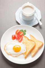 breakfast with fried eggs and toasts on wooden table