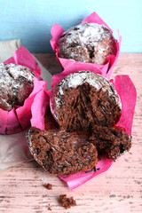 Chocolate cupcakes in pink paper on wooden table, closeup