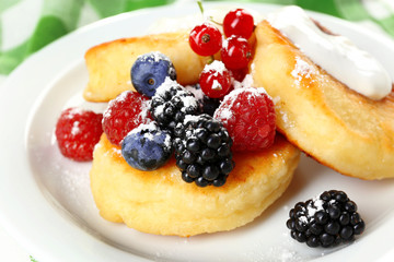 Fritters of cottage cheese with berries in plate, closeup