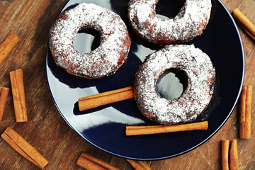 Delicious doughnuts with chocolate icing and cinnamon on table close up