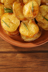 Delicious baked potato with rosemary in bowl on table close up