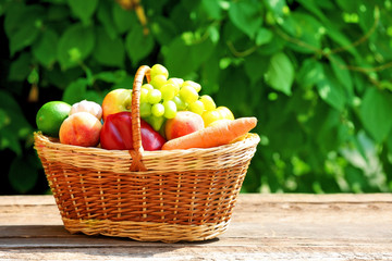 Heap of fresh fruits and vegetables in basket on table outdoors