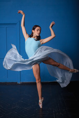 Fototapeta premium young modern ballet dancer posing on blue background