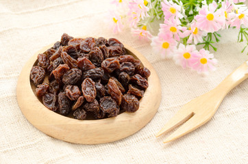 Raisin on wooden dish and wooden fork spoon.