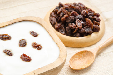 Home sweet yogurt with raisins in a wooden bowl.