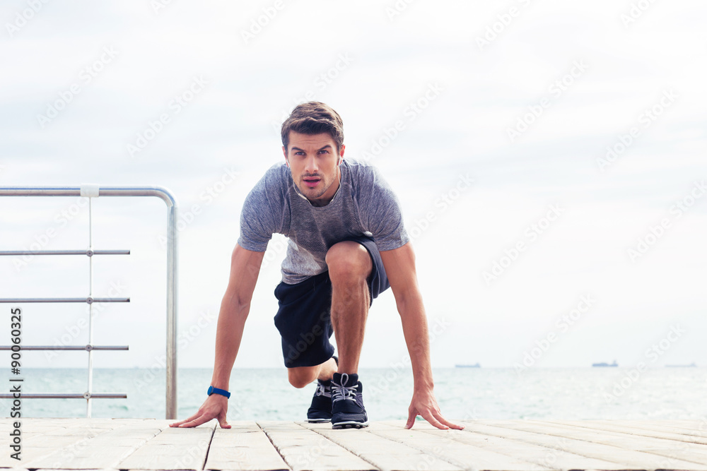 Wall mural Runner standing in start position outdoors