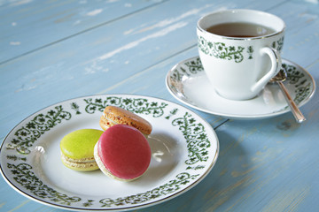 Macarons with a cup of tea on wooden table.