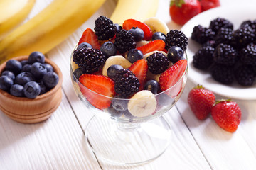 Salad strawberry banana blueberries and blackberries on white boards.