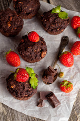Chocolate cupcakes with strawberries on wooden background