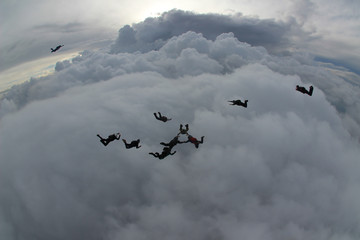 Skydiving group of people above the clouds