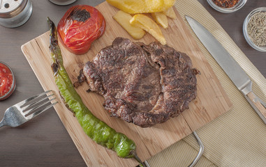 Grilled beef steak served with grilled tomatoes, peppers and chips