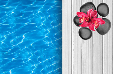 Swimming pool and wooden deck with spa stones and pink orchid as