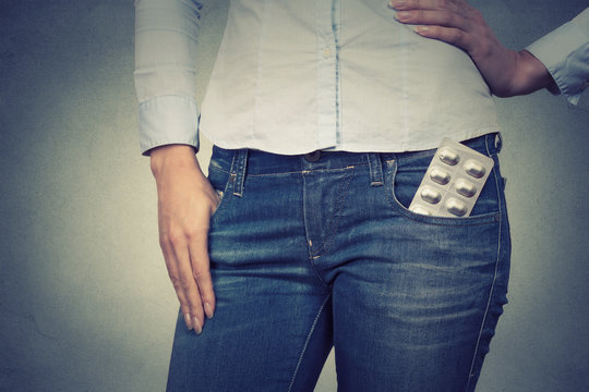 Closeup cropped image of a woman with pills in her pocket on gra
