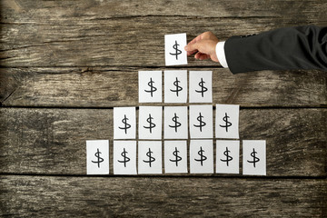 Overhead view of businessman arranging dollar sign in pyramid shape