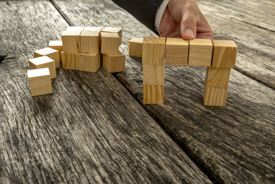 Close up of businessman forming a bridge of small wooden blocks