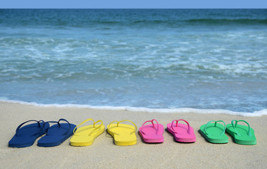 family colorful flip flop sandals on on the beach