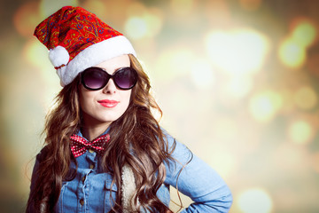 Content brunette female in Christmas hat and sunglasses studio - obrazy, fototapety, plakaty