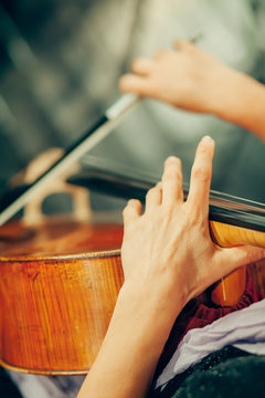 Symphony orchestra on stage, hands playing cello