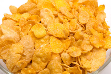 corn flakes in a glass bowl on white background shot from above