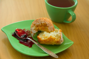 In the green bowl of fresh homemade muffin with jam and a cup of black tea