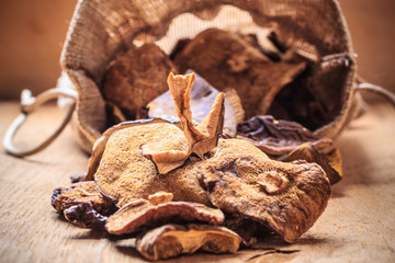 Dry mushrooms in sack on wooden table.