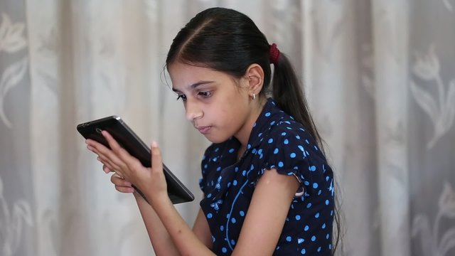 indian girl playing games on a tab and showing thumbs up after getting a winning point
