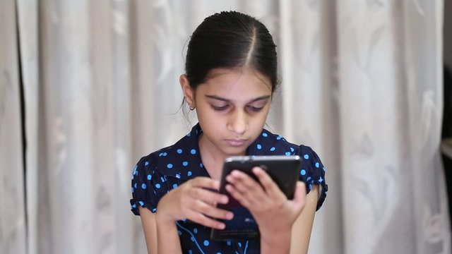 indian girl playing games on a tab and showing thumbs up after getting a winning point