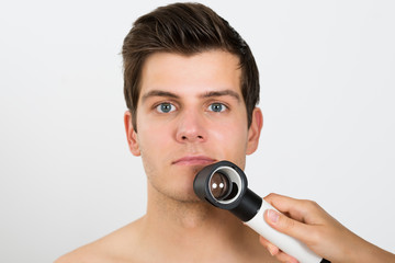 Person Examining Man Face With Dermatoscope