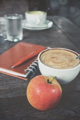 Apple and blank notepad with coffee on office table