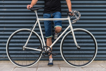 Fototapeta na wymiar Hipster man with a fixie bike in metallic wall