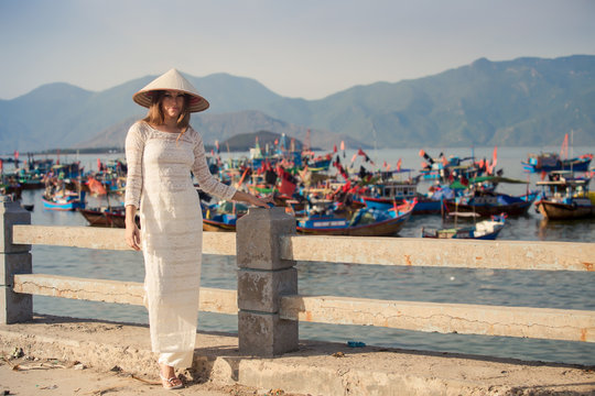 blonde girl in Vietnamese dress leans on embankment