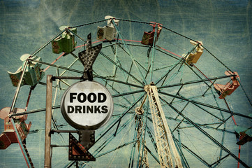 aged and worn vintage photo of food and drinks sign at carnival with ferris wheel